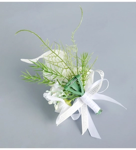 Detail of white calla lily corsage featuring satin ribbon and brooch pin fastener