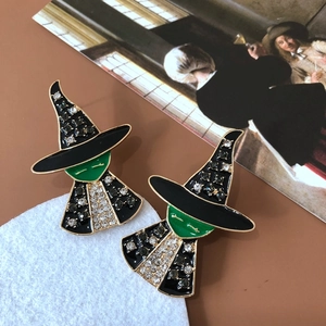 Detail view of witch-shaped earrings with black and green enamel and sparkling rhinestones