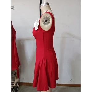 Détail de robe courte rouge moulante avec fleur 3D blanche et accents en strass chic