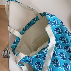 Detail view of large canvas tote bag with floral prints showing spacious beige interior pocket