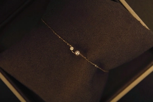 Macro detail of S925 silver 18K gold bracelet with a pearl and zircon on velvet