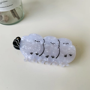 Detailed view of bird-shaped acetate hair claw clips with purple and white marble texture