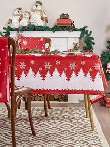 Detail van rood kersttafelkleed en stoelhoezen met sneeuwvlok en boom patronen