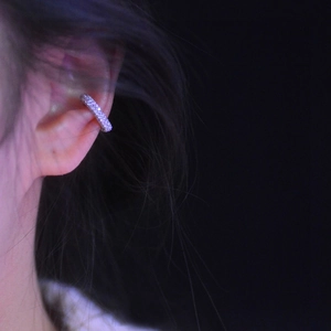 Sparkling zircon heart-shaped ear cuff in silver finish worn on ear with dark background
