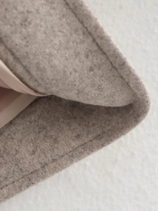 Detail der grauen Tweed-Struktur mit glattem rosa Satinfutter am Saum der Jacke