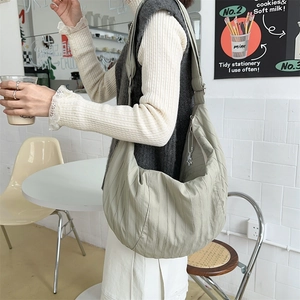 Detailed side view of large grey-green dumpling bag with textured nylon and star charm
