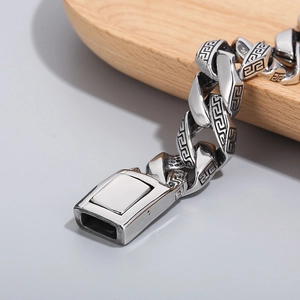 Macro shot of vintage stainless steel Cuban link bracelet with Greek key engraving