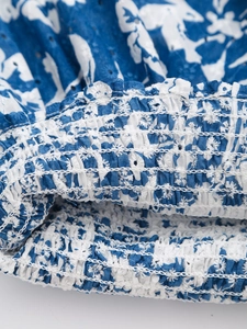 Dettaglio macro dell'orlo elastico con ricamo a occhielli blu su un top con scollo a V