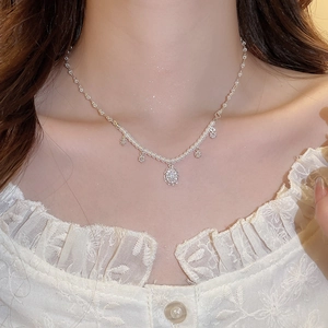 Detail of silver pearl necklace with zircon pendant worn on an elegant model neckline