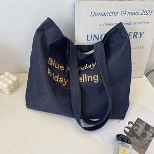 Dettaglio ricamo dorato su borsa tote in denim blu scuro di alta qualità per uso quotidiano