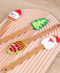 Set of four Christmas silicone spatulas with wooden handles on a round tray for baking