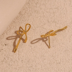 Detail of 18K gold plated stainless steel bow earrings with a polished metallic finish