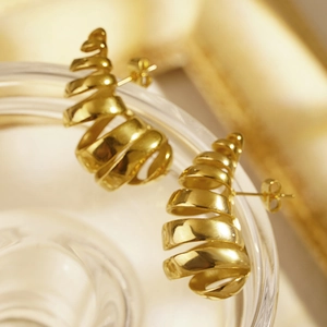 Vintage golden stainless steel croissant stud earrings on glass surface in warm light