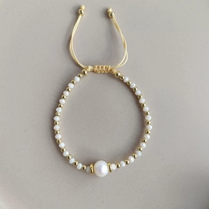 Detail of adjustable pearl bracelet with gold beads and white faceted stones on cord