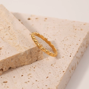 Minimalist 18k gold plated stainless steel wave textured ring on a stone pedestal