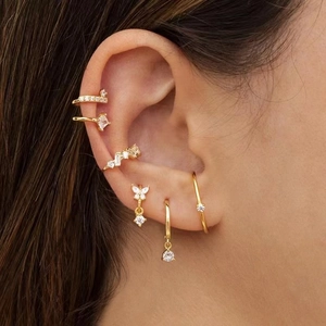 Close-up of gold butterfly earrings and ear cuffs with sparkling crystals on ear