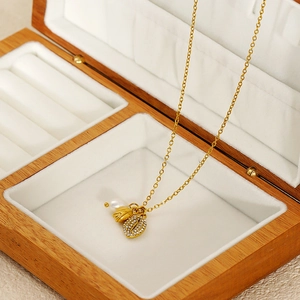 Detail of gold shell necklace with pearl and rhinestone leaf pendant in a jewelry box