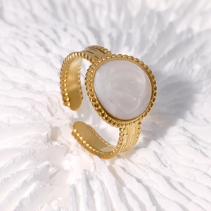 Gros plan de la bague dorée vintage avec insert ovale blanc et bordure perlée élégante