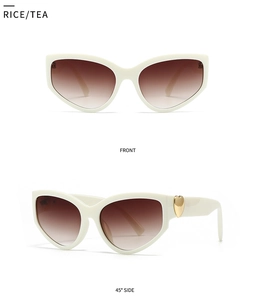 Detail of beige cat eye sunglasses with brown gradient lenses and gold heart metal accents