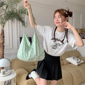 Close-up of green floral canvas tote bag shown in a cozy indoor lifestyle setting