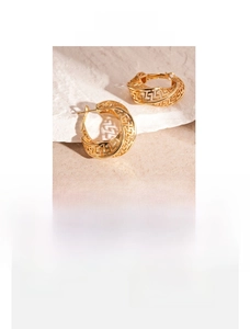 Detailed macro view of vintage hollowed copper hoop earrings with Greek key patterns