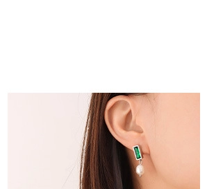 Gros plan de boucles d'oreilles en argent avec pierre verte et perles portées par un mannequin