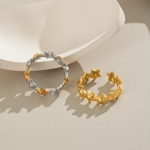 Minimalist gold and silver star-shaped open rings displayed on a geometric stone pedestal
