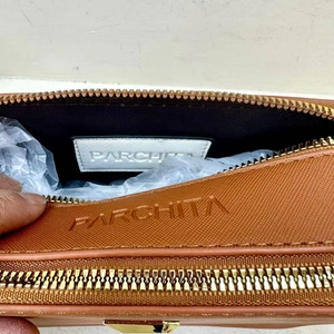 Detail view of brown leather handbag top zipper and interior branding with hand
