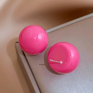 Close-up of bright pink spherical resin stud earrings with silver metal needles