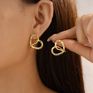 Detail of 18k gold plated hollow heart-shaped stud earrings worn by a female model