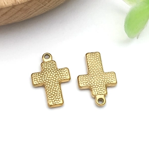 Detail of golden stainless steel cross pendants with intricate beaded relief texture