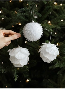 Close-up of hand picking white glittery pinecone and furry ball ornaments on a Christmas tree