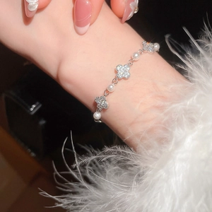 Detail of elegant silver clover bracelet with sparkling zircons and round white pearls