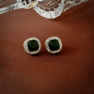 Detail of square black stud earrings with silver metal base and white crystal halo