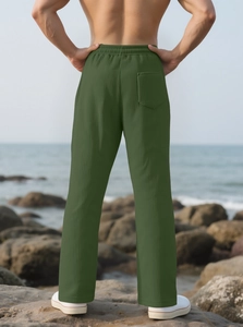 Outdoor back view of men's olive green wide-leg trousers with ribbed texture by the sea