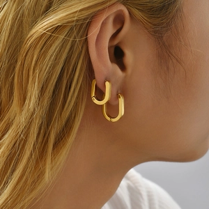 Classic 18K gold plated stainless steel oval hoop earrings shown worn on female model