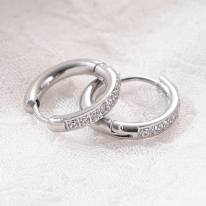 Close-up of silver-tone hoop earrings with micro-paved cubic zirconia on white lace background