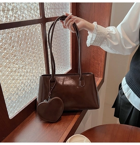 Detail of dark brown vintage leather tote bag with a heart-shaped zipper pouch attachment