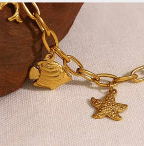 Macro detail of gold plated necklace featuring starfish and tropical fish sea charms