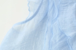 Close-up of light blue pleated chiffon shoulder with elegant ruffle trim detail
