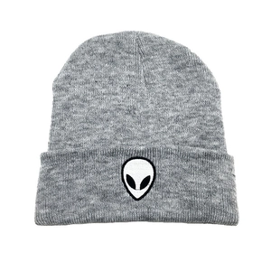 Close-up of a grey knitted beanie featuring a detailed black and white alien embroidery