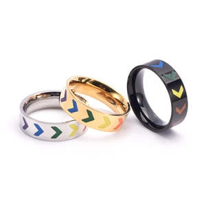 Macro shot of silver, gold, and black titanium V-shaped rings with rainbow enamel arrows