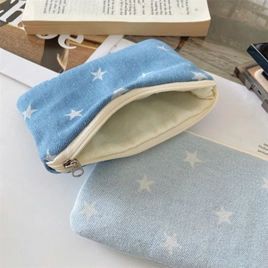 Detail of denim cosmetic bags showing white star prints and high-quality metal zippers