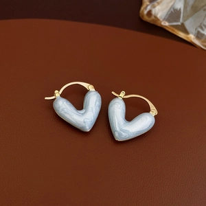 Vue macro de boucles d'oreilles cœur marbré bleu plaqué or sur fond en cuir marron