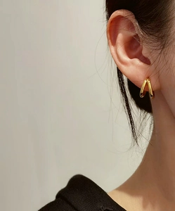 Close-up of elegant double-layered gold hoop earrings worn by a model in soft light