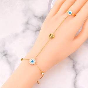Gold evil eye finger bracelet ring set with blue zircon accents on marble background