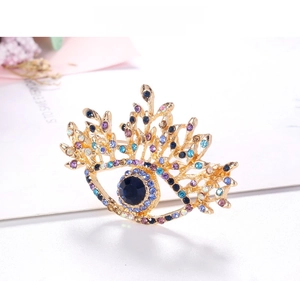 Detailed macro view of an eye-shaped brooch with blue crystals on a golden alloy frame