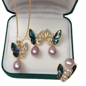 Golden butterfly jewelry set with purple pearls and shimmering shell inlay in a velvet box