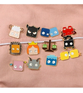 Collection of 12 cartoon zodiac metal badges with enamel finish on pink fabric