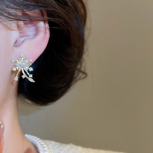 Macro shot of snowflake pearl earrings with cubic zirconia and gold finish on model ear